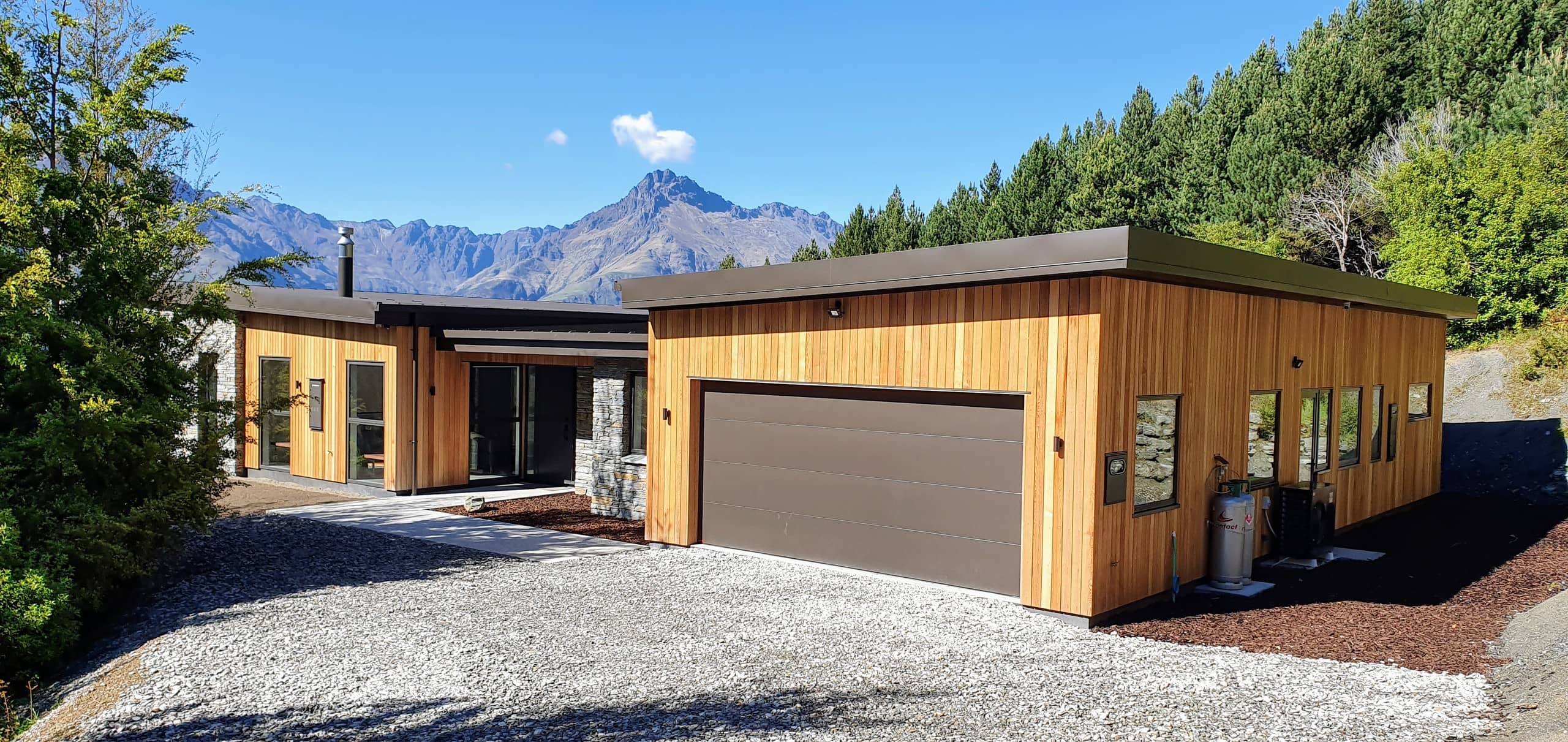Single-storey home in timber and stone with garaging, the mountains behind