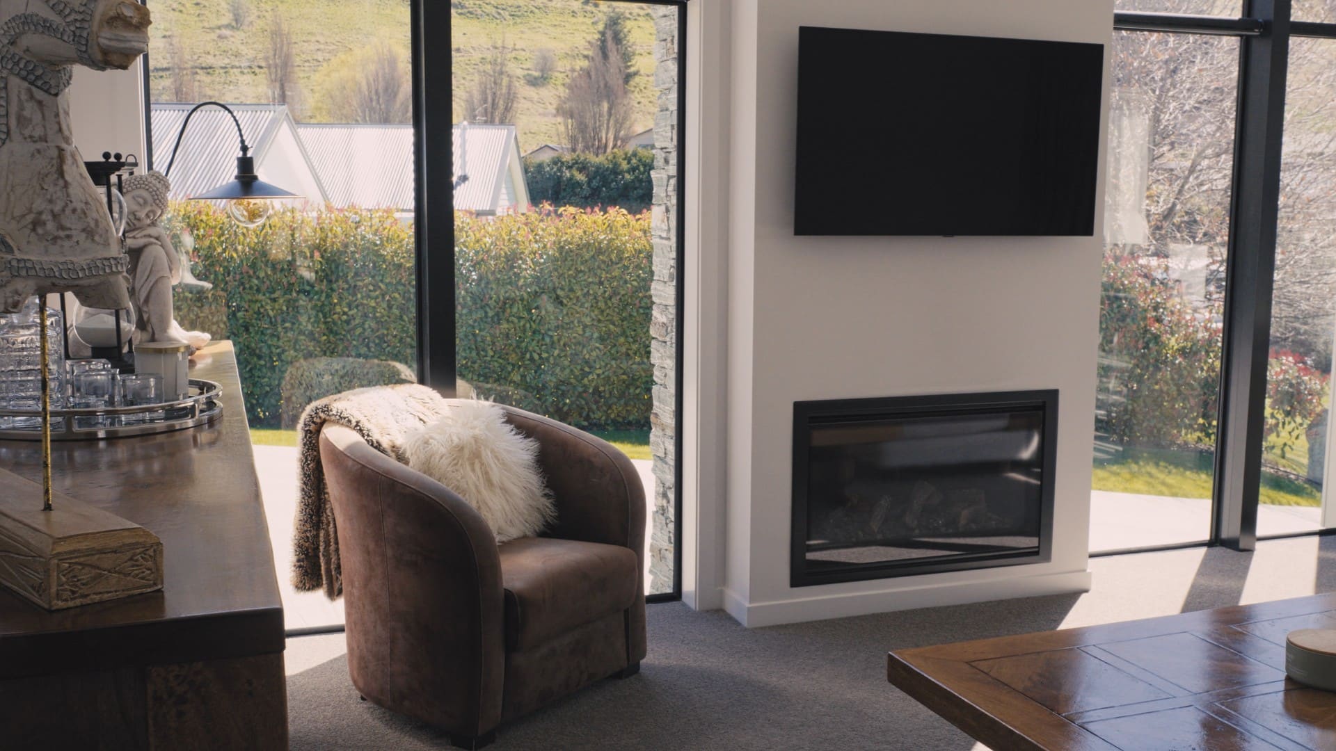 Armchair beside the fire, with the garden reflected in the glazing
