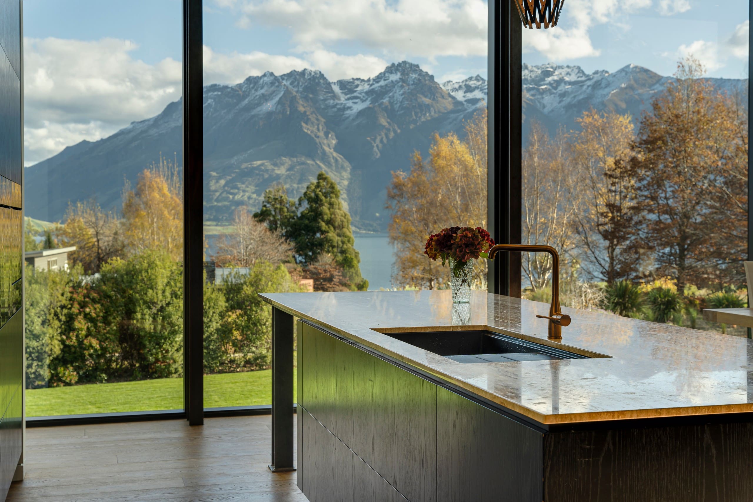 Kitchen island beneath full-height glazing looking out to the lake and mountains