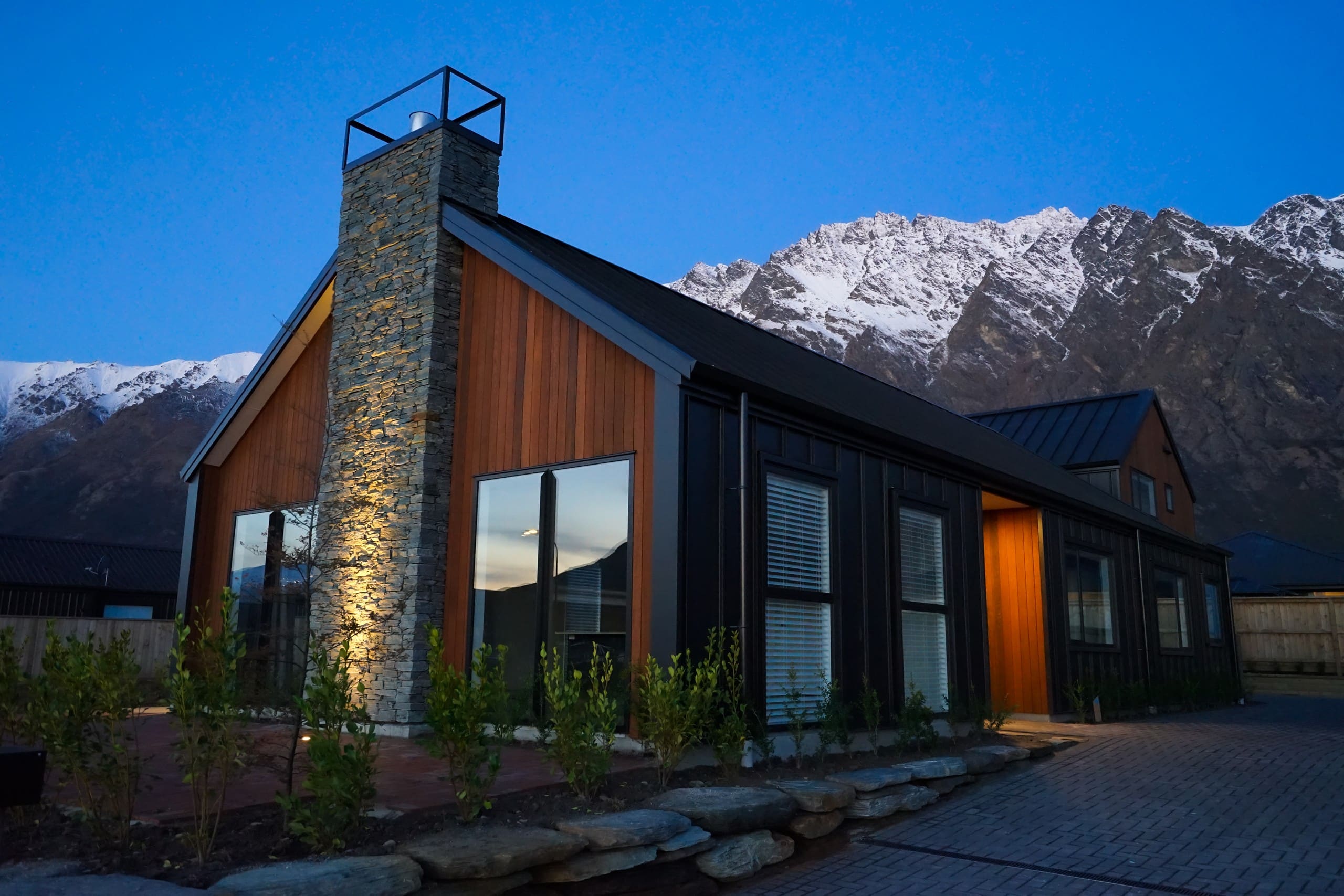 Gable home in timber and stone, lit at dusk beneath the Remarkables